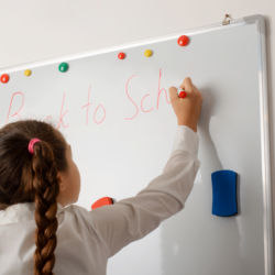 A child writing back to school on a whiteboard